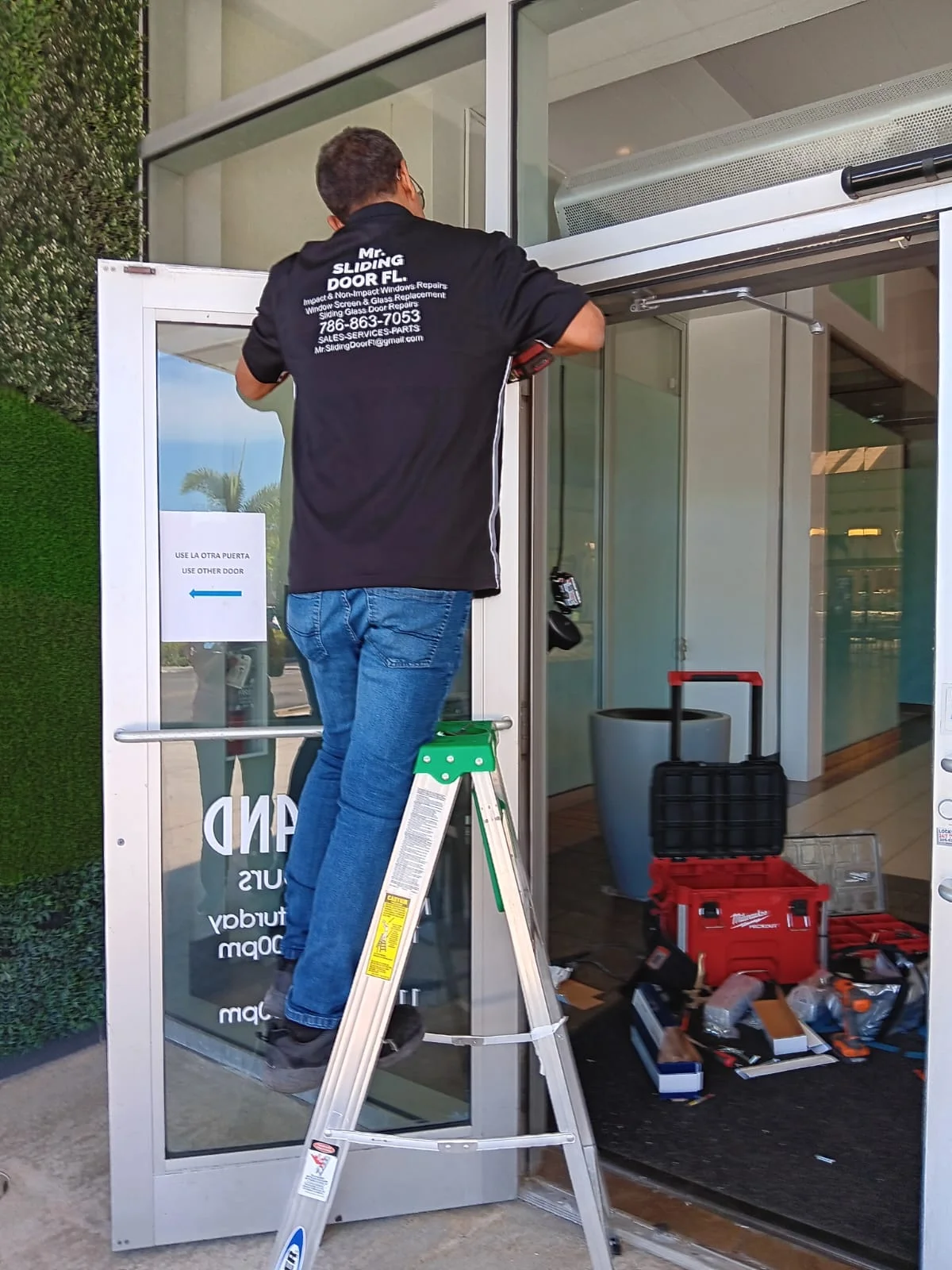 Technician repairing a commercial glass door entry in South Florida